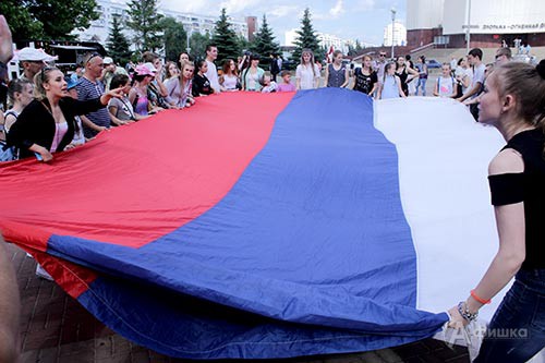 Участники флеш-моба разворачивают огромное полотнище флага России